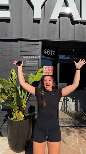 A member cheering with a DropKick 4-pack on her head
